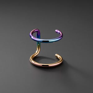 May include: A double-band ear cuff featuring a smooth, polished finish. The top band displays a vibrant iridescent gradient transitioning from purple to blue, while the bottom band features a warm, metallic rose gold tone with a reflective surface.