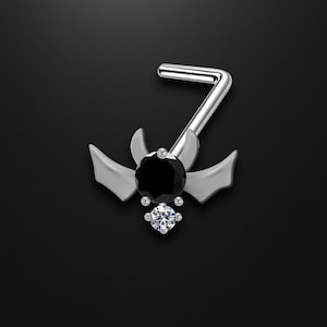 May include: A silver nose ring featuring a bat-wing design. The jewelry has a large black gem in the center, a smaller clear gem below, and a bent post for insertion. The wings and post are silver.