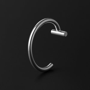 Könnte beinhalten: Ein poliertes silbernes Metallarmband mit einem gebogenen, kreisförmigen Design. Das Armband hat einen zylindrischen Stab, der mit dem Hauptband verbunden ist. Der Hintergrund ist einfarbig schwarz.