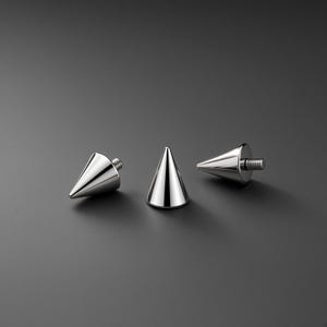 Peut inclure: Trois clous coniques en métal argenté poli avec des tiges filetées à la base. Chaque clou présente une surface lisse et réfléchissante ainsi qu'une pointe effilée, conçus pour être fixés sur divers matériaux grâce au mécanisme de vis intégré.