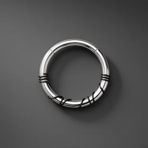 May include: A circular silver-toned hoop ring featuring a smooth metallic finish. The hoop is accented with thin, black wire wrapped around the band at two distinct sections, creating a contrasting visual detail on the polished metal surface.