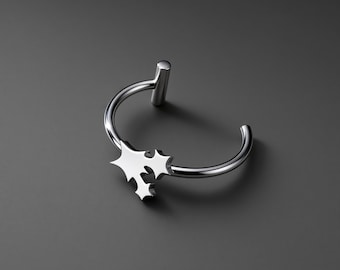 May include: A silver-toned metal ring featuring an open band design. One end of the band terminates in a small cylindrical post, while the other end is adorned with a cluster of three interconnected star-shaped cutouts with pointed edges.