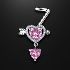 Könnte beinhalten: Ein silberfarbener Bauchnabelring mit einem herzförmigen rosa Edelstein, der von kleinen, klaren Steinen umgeben ist. Ein Pfeil durchbohrt das Herz, und ein kleineres Herz baumelt darunter. Das Design ist vor schwarzem Hintergrund.