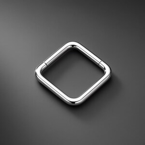 Könnte beinhalten: Ein polierter, silberfarbener Metallring in quadratischer Form mit abgerundeten Ecken. Der Ring verfügt über einen nahtlosen Klappverschluss, der an den Seiten sichtbar ist und eine durchgehende, glatte und reflektierende Oberfläche erzeugt.