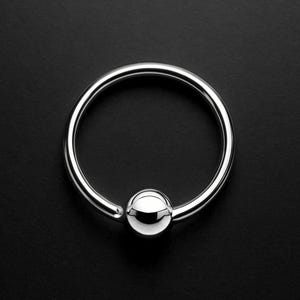 May include: A shiny, silver-colored captive bead ring. The ring is circular with a small, round bead that secures the ring's closure. The jewelry is set against a black background.