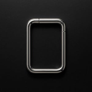 May include: A polished, rectangular metal handle with rounded corners, set against a stark black background. The handle is a continuous loop, with a small gap at the top. The reflective surface of the metal creates highlights and shadows.