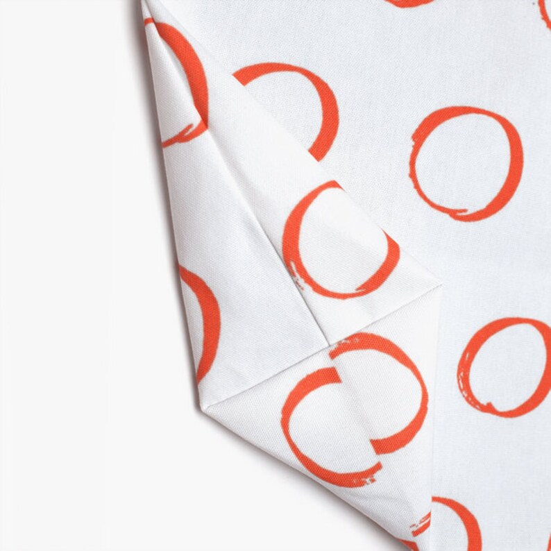 May include: White fabric with a repeating pattern of orange circles. The circles are hand-painted and have a slightly uneven texture.