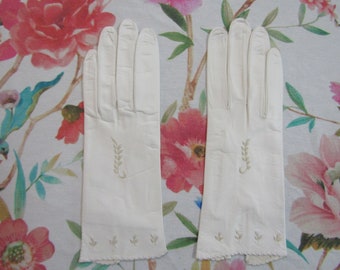Puede incluir: Un par de guantes color crema con un diseño bordado en forma de trigo. Los guantes tienen un borde festoneado y están hechos de un material suave. Un accesorio clásico.