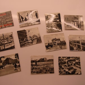 May include: A selection of vintage black and white postcards showing historical scenes. The postcards depict cityscapes, architecture, and street scenes. One postcard has the text "Berlin Europa" in red.