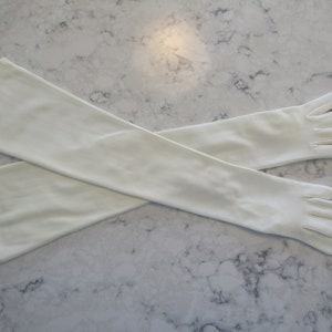 Peut inclure: Une paire de longs gants blancs avec des doigts sans doigts. Les gants sont faits d'un tissu doux et extensible et sont parfaits pour ajouter une touche d'élégance à n'importe quelle tenue.