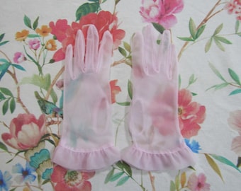 Könnte beinhalten: Ein Paar rosa, durchsichtige Handschuhe mit Rüschen. Die Handschuhe sind aus einem zarten Stoff und haben ein Blumenmuster.