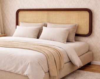 May include: A bed featuring a woven rattan headboard with a dark brown wooden frame. The bed is made up with beige bedding, pillows, and a tan throw. The bed frame is upholstered in a light beige fabric.
