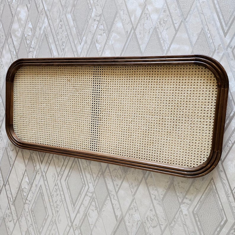 May include: Rectangular wooden frame with a woven cane insert. The frame has rounded corners and a dark brown finish. The cane insert is a light beige color and has a grid-like pattern.