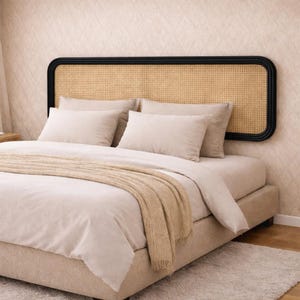 May include: A bed with a beige upholstered frame, adorned with matching pillows and bedding. A woven headboard with a black frame adds a contrasting element. A tan throw blanket is draped across the bed, creating a cozy and inviting atmosphere.