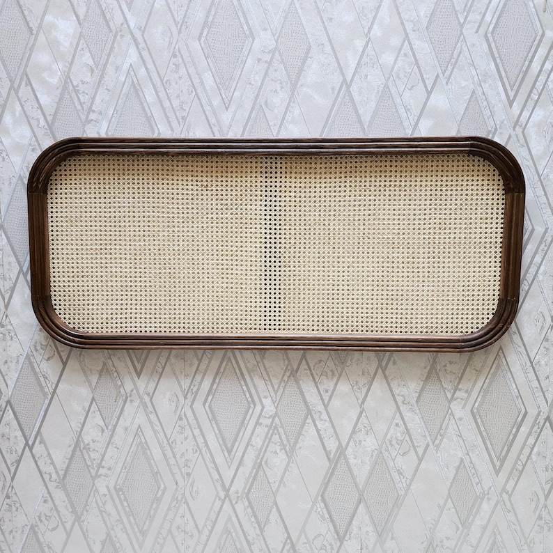 May include: Rectangular woven rattan tray with a dark brown wooden frame. The tray features a light beige woven center and rounded corners. The frame is a rich, dark brown color. The tray is designed for decorative or functional use.