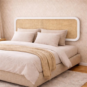 May include: A beige bed with a woven headboard and matching bedding. The headboard has a white frame and a woven cane insert. Beige pillows and a blanket are arranged on the bed, creating a cozy and inviting atmosphere.
