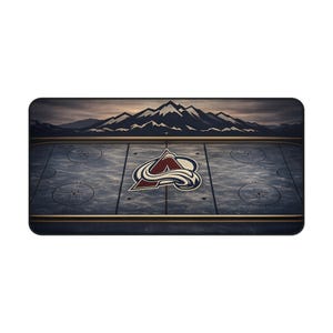 May include: Rectangular mat featuring a hockey rink design with the Colorado Avalanche logo at center ice. The background shows a mountain range under a cloudy sky. The mat has a dark blue and brown color scheme.
