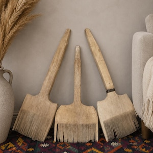 Puede incluir: Tres peines de lino antiguos de madera con mangos largos de color claro y filas de dientes metálicos finos y verticales en la base. Las herramientas presentan una textura de veta de madera natural desgastada y están dispuestas en abanico.