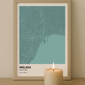 May include: Framed map art print of Málaga, Spain, in teal and white. The print includes the city's name and country. A lit candle sits in front of the framed print. The words "DIGITAL download" are in the top left corner.