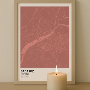 Puede incluir: Una impresión enmarcada del mapa de Badajoz, España, en un tono rojo apagado. El mapa detalla las calles de la ciudad y el río Guadiana. La impresión está etiquetada como "Badajoz España" e incluye una vela.