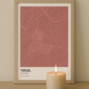 Puede incluir: Una impresión enmarcada del mapa de Teruel, España, en un tono rojo apagado. El mapa detalla el diseño de la ciudad con carreteras y características. La impresión está etiquetada como "TERUEL ESPAÑA". Una vela encendida está al frente.