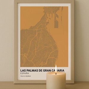 Puede incluir: Impresión artística enmarcada del mapa de Las Palmas de Gran Canaria, España, en tonos marrones y beige. La impresión incluye el texto "LAS PALMAS DE GRAN CANARIA ESPAÑA" y "Maptone Atardecer". Una vela encendida está delante.
