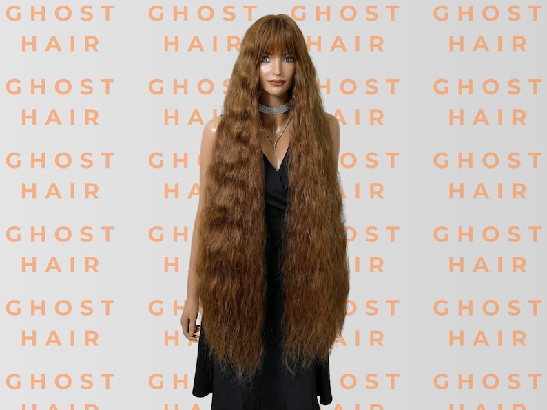 May include: A mannequin displays a long, auburn wig with a fringe. The wig has a wavy texture and falls well below the waist. The background is patterned with the words "GHOST HAIR" in a light orange hue.