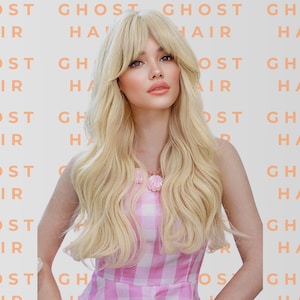 May include: A woman with long, wavy blonde hair and bangs, wearing a pink and white checkered dress. The background features the words "GHOST HAIR" in a repeating pattern. She is also wearing a pink seashell necklace.