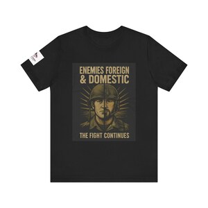May include: Black t-shirt with a graphic of a soldier in a military helmet. The graphic has the text "Enemies Foreign & Domestic" and "The Fight Continues".