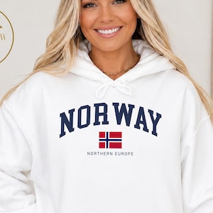 以下が含まれることがあります： 胸の中央に濃い青色の大きな文字でNORWAY、その下に小さなノルウェー国旗のグラフィック、さらにその下に濃い青色の小さな文字でNORTHERN EUROPEとプリントされた、白いフード付きスウェットシャツ。