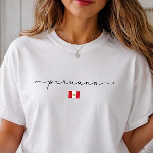 Peut inclure: T-shirt blanc avec le mot "peruana" en écriture cursive et un petit drapeau péruvien. Le t-shirt est fait d'une matière douce et convient aux tenues décontractées. Le t-shirt est de style col rond.