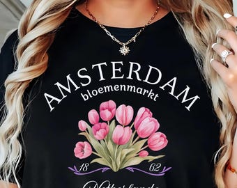 May include: Black t-shirt with the words "AMSTERDAM bloemenmarkt" and a floral design of pink tulips. The shirt also features the text "18 62 Netherlands". The t-shirt is black.