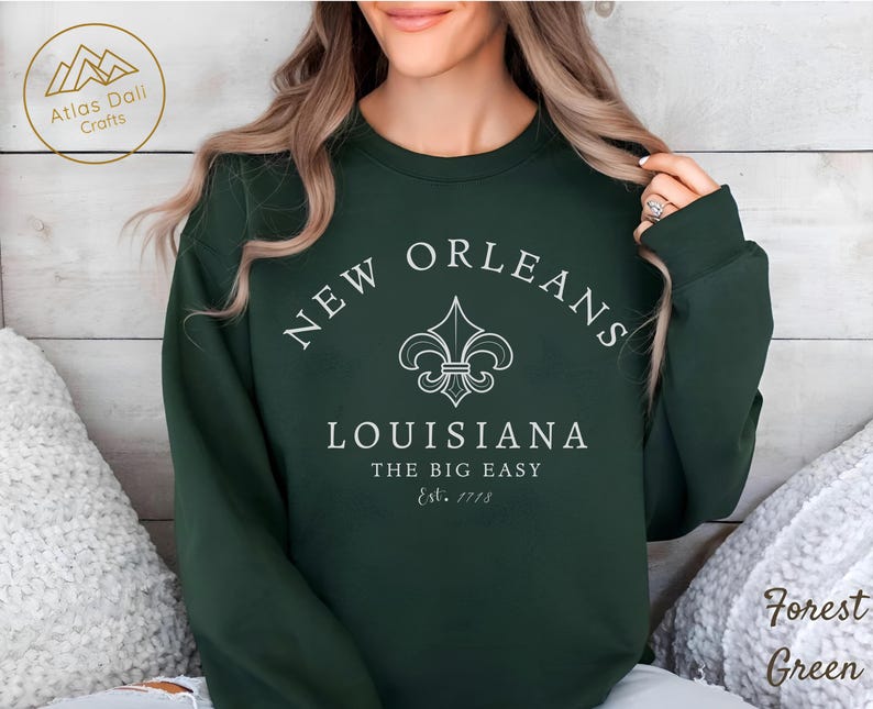 May include: Forest green sweatshirt with the text "NEW ORLEANS LOUISIANA THE BIG EASY Est. 1718" in white. The design includes a fleur-de-lis symbol. The sweatshirt is a crew neck style.