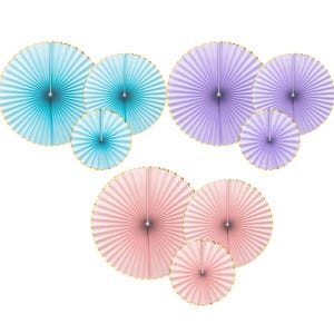Pode incluir: Uma coleção de decorações de leques de papel em tons de azul, roxo e rosa. Cada leque tem uma borda dourada e um acento metálico central. Os leques são dispostos em grupos de vários tamanhos, criando uma exibição decorativa de arte de parede.