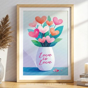May include: A framed art print showing a white vase with heart-shaped flowers in pink and orange, with green leaves. The vase has the text "Love is Love" in pink. The background is a soft blue. The frame is made of wood.