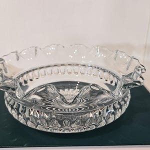 Könnte beinhalten: Transparente Glasschale mit gewelltem Rand. Die Schale hat einen dekorativen, gemusterten Boden und einen gewellten Rand. Das transparente Glas lässt Licht durch und eignet sich zum Servieren verschiedener Gerichte.