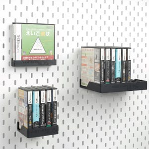 May include: Black metal shelves displaying Nintendo DS game cartridges. The shelves are mounted on a white pegboard wall. The game cases have Japanese text and colourful graphics. The shelves are labelled with the Nintendo DS logo.