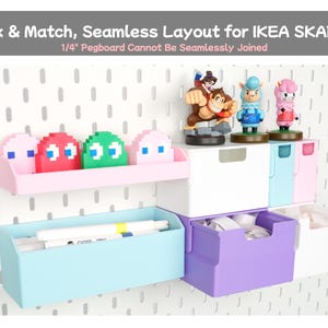 May include: A white pegboard wall organiser system featuring pastel-coloured storage bins, shelves, and drawers. The display includes pixelated ghost figures, small character figurines, and markers. Text reads: Mix & Match, Seamless Layout for IKEA SKADIS.