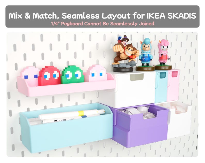 May include: A white pegboard wall organiser system featuring pastel-coloured storage bins, shelves, and drawers. The display includes pixelated ghost figures, small character figurines, and markers. Text reads: Mix & Match, Seamless Layout for IKEA SKADIS.