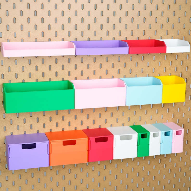 May include: A collection of colourful plastic storage bins and open containers mounted on a pegboard. The set includes various rectangular shapes in shades of pink, purple, red, white, green, blue, yellow, and orange, featuring open-top designs.