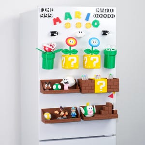 Op de afbeelding: Een verzameling kleurrijke Super Mario-thema koelkastmagneten. De set bevat verschillende personages, vraagtekenblokken, buizen en andere iconische elementen uit de videogame. De magneten zijn gerangschikt op een witte koelkastdeur.