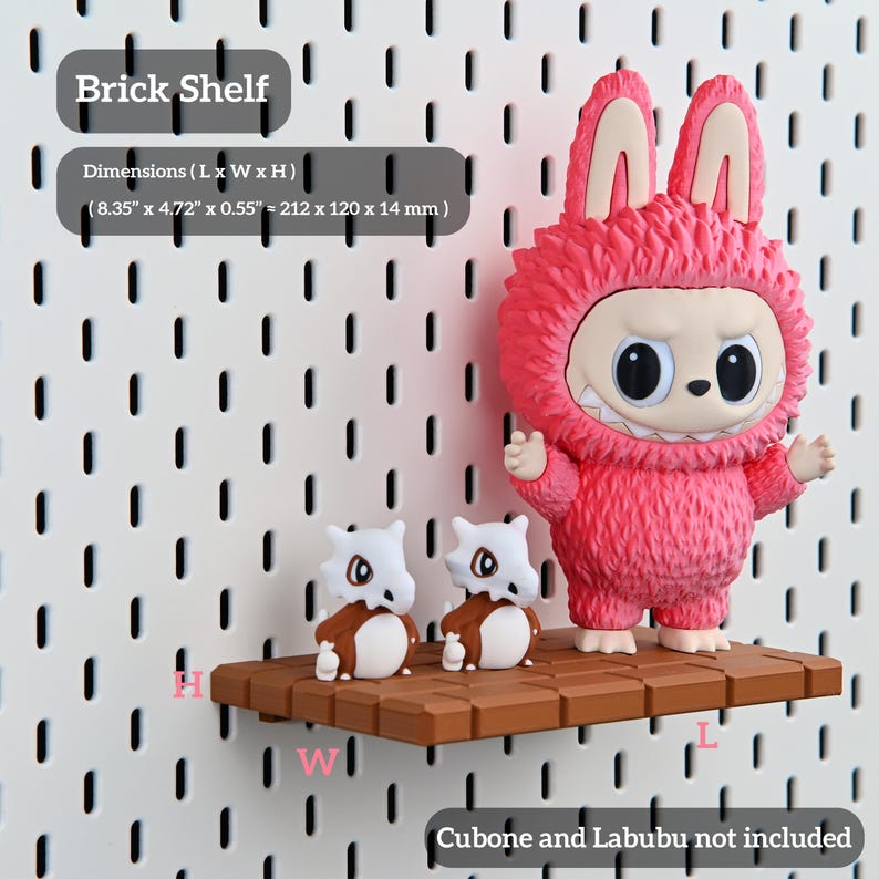 Puede incluir: Una estanter&iacute;a de ladrillo marr&oacute;n de 212 x 120 x 14 mm, que muestra una figura rosa y peluda de Labubu y dos figuras de Cubone. La estanter&iacute;a est&aacute; montada en una pared perforada blanca. El texto de la imagen dice "Brick Shelf" y "Cubone and Labubu not included."