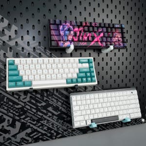 May include: A set of three ceramic mugs with a speckled, matte finish. The mugs are in shades of cream, light gray, and dark gray. Each mug has a simple, modern design and a rounded handle.