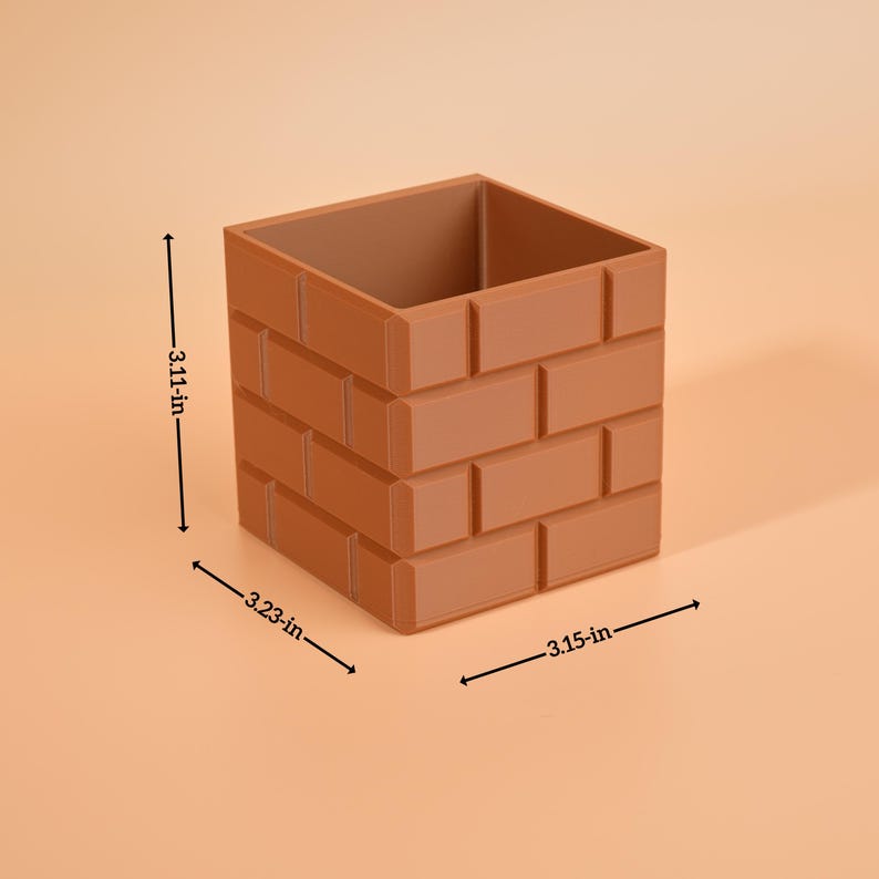 May include: A brown, brick-effect container, measuring 7.9 cm high, 8.2 cm wide, and 8 cm deep. The square-shaped container has a hollow interior and is designed to resemble a brick wall. The product is suitable for home decor.