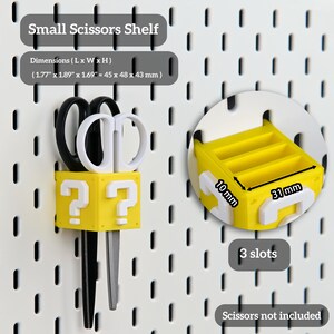 Puede incluir: Un peque&ntilde;o estante amarillo y blanco para tijeras con un dise&ntilde;o de signo de interrogaci&oacute;n. El estante mide 45 x 48 x 43 mm. La imagen tambi&eacute;n muestra un estante amarillo con 3 ranuras, que mide 10 mm x 31 mm.