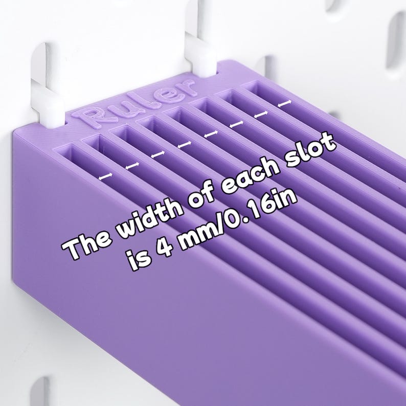 Puede incluir: Un organizador de pl&aacute;stico morado con m&uacute;ltiples ranuras paralelas, montado en un tablero perforado blanco. La palabra Ruler est&aacute; grabada en el borde superior. El texto indica: The width of each slot is 4 mm/0.16in, con flechas de medida.