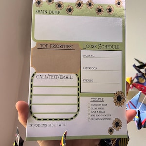 May include: ADHD daily planner with a green and tan floral design. The planner includes sections for a brain dump, top priorities, a loose schedule, and a checklist for the day. The text "ADHD Daily Planner" is at the top.