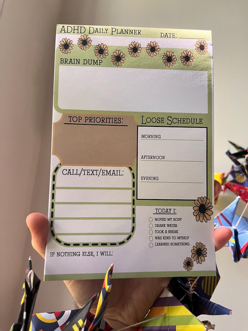 May include: ADHD daily planner with a green and tan floral design. The planner includes sections for a brain dump, top priorities, a loose schedule, and a checklist for the day. The text "ADHD Daily Planner" is at the top.