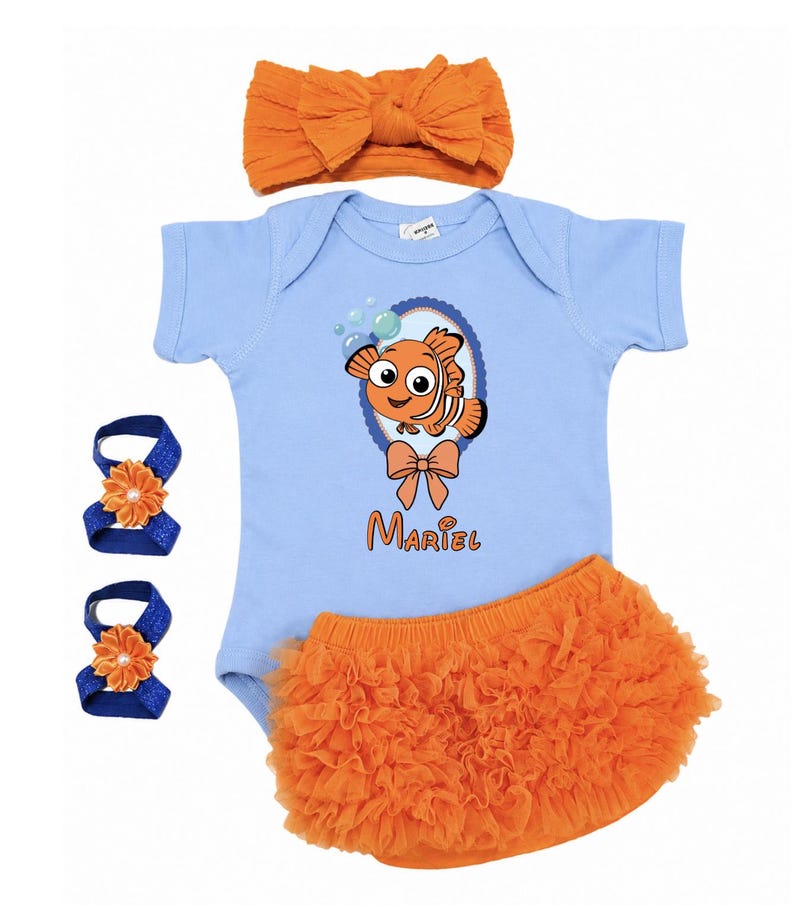 Pu&ograve; includere: Un set di abbigliamento per neonati con un body azzurro chiaro con una grafica di pesce dei cartoni animati, bloomers arancioni a balze, una fascia per capelli con fiocco arancione abbinata e due fasce per i piedi con fiori blu e arancioni. Il nome "Mariel" &egrave; stampato sul body.
