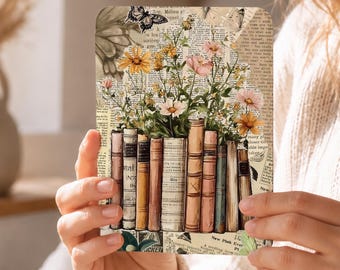 May include: A square coaster with a vintage design, showing a collage of books, flowers, and butterflies. The image uses aged paper textures and soft colours, with a bouquet of pink and yellow flowers above a row of books.